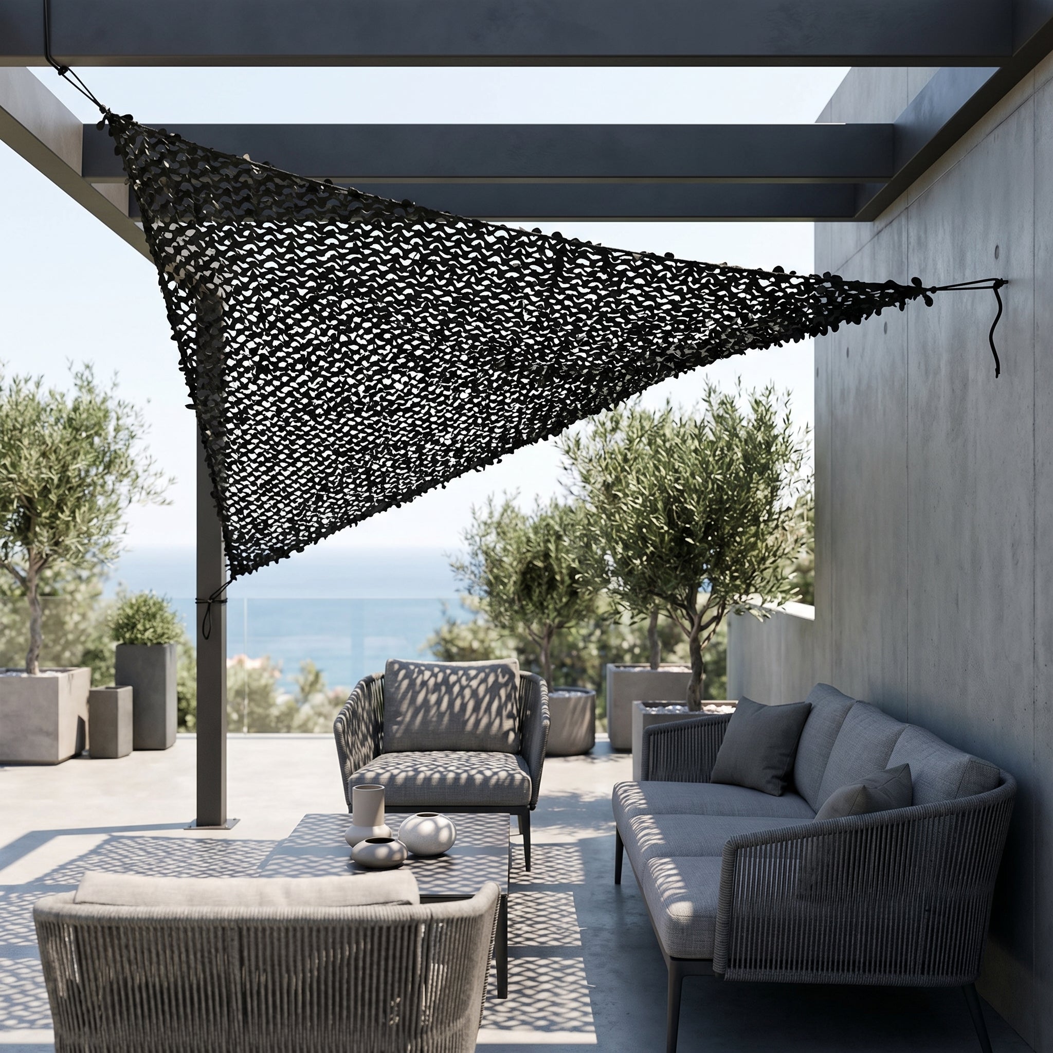 Filet de camouflage triangulaire noir Camofil installé au-dessus d'un salon de jardin moderne sur une terrasse.