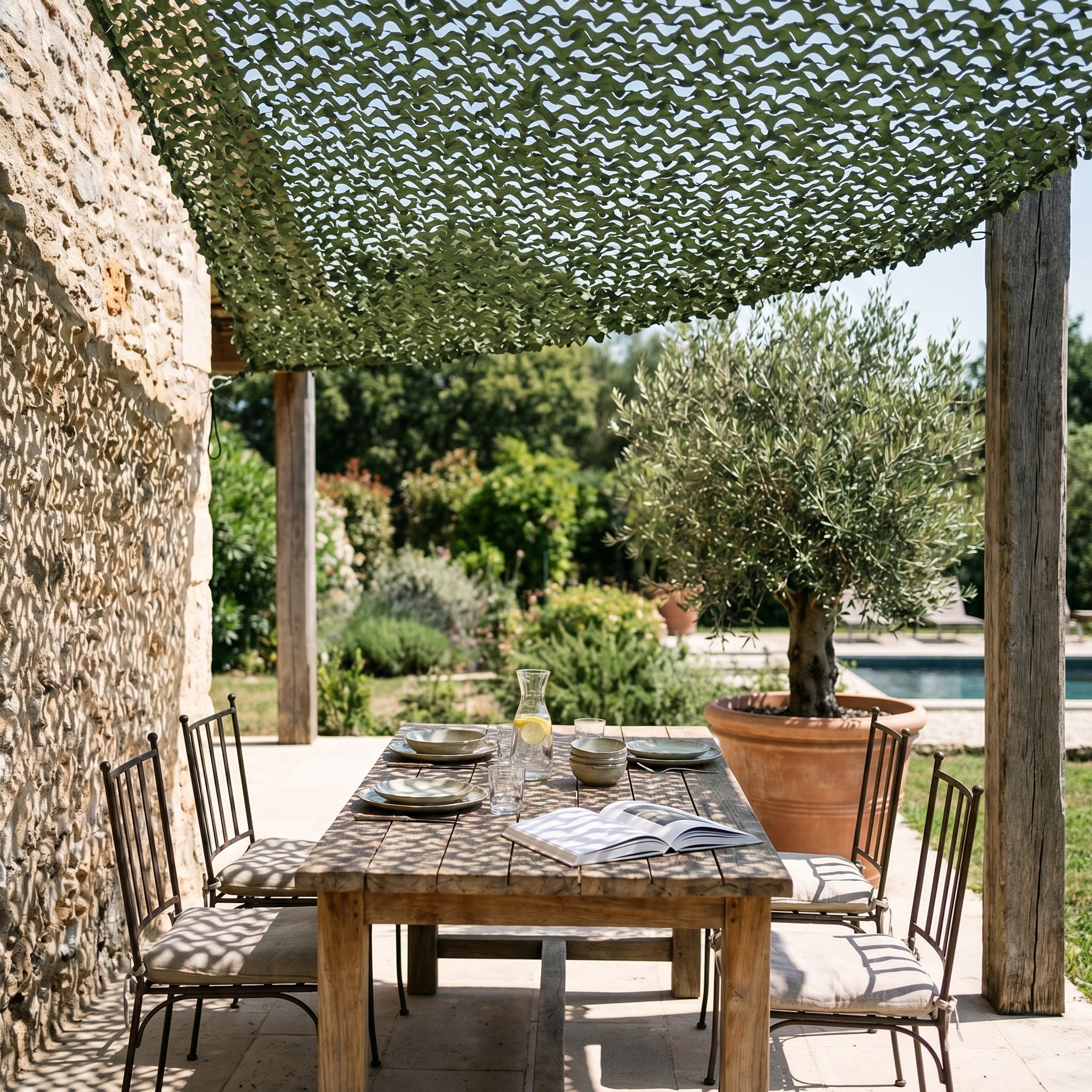 Filet de camouflage triangulaire vert Camofil installé au-dessus d'une table de repas sur une terrasse.