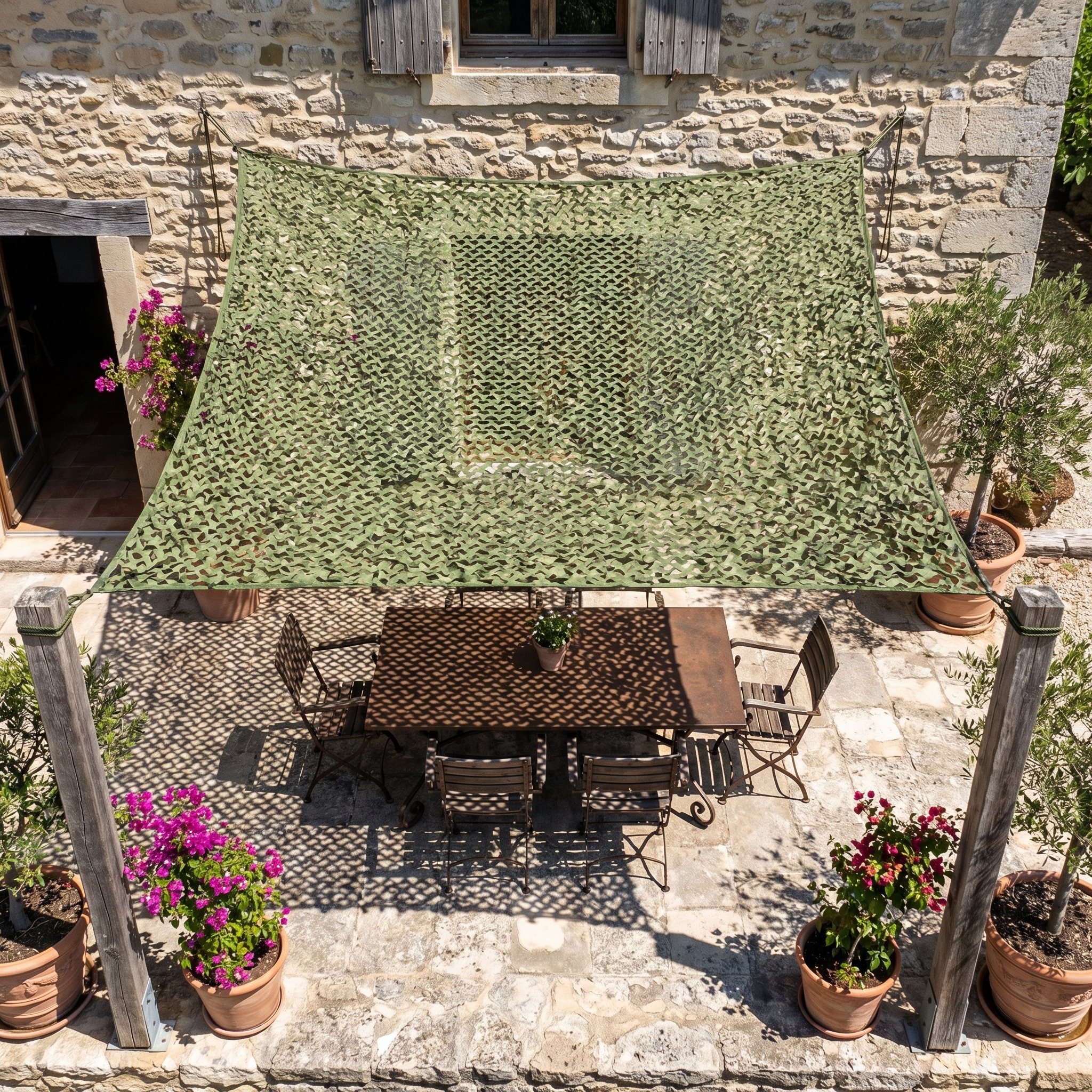 Filet de camouflage renforcé vert ombrageant une table de repas dans un patio en pierre de style rustique.