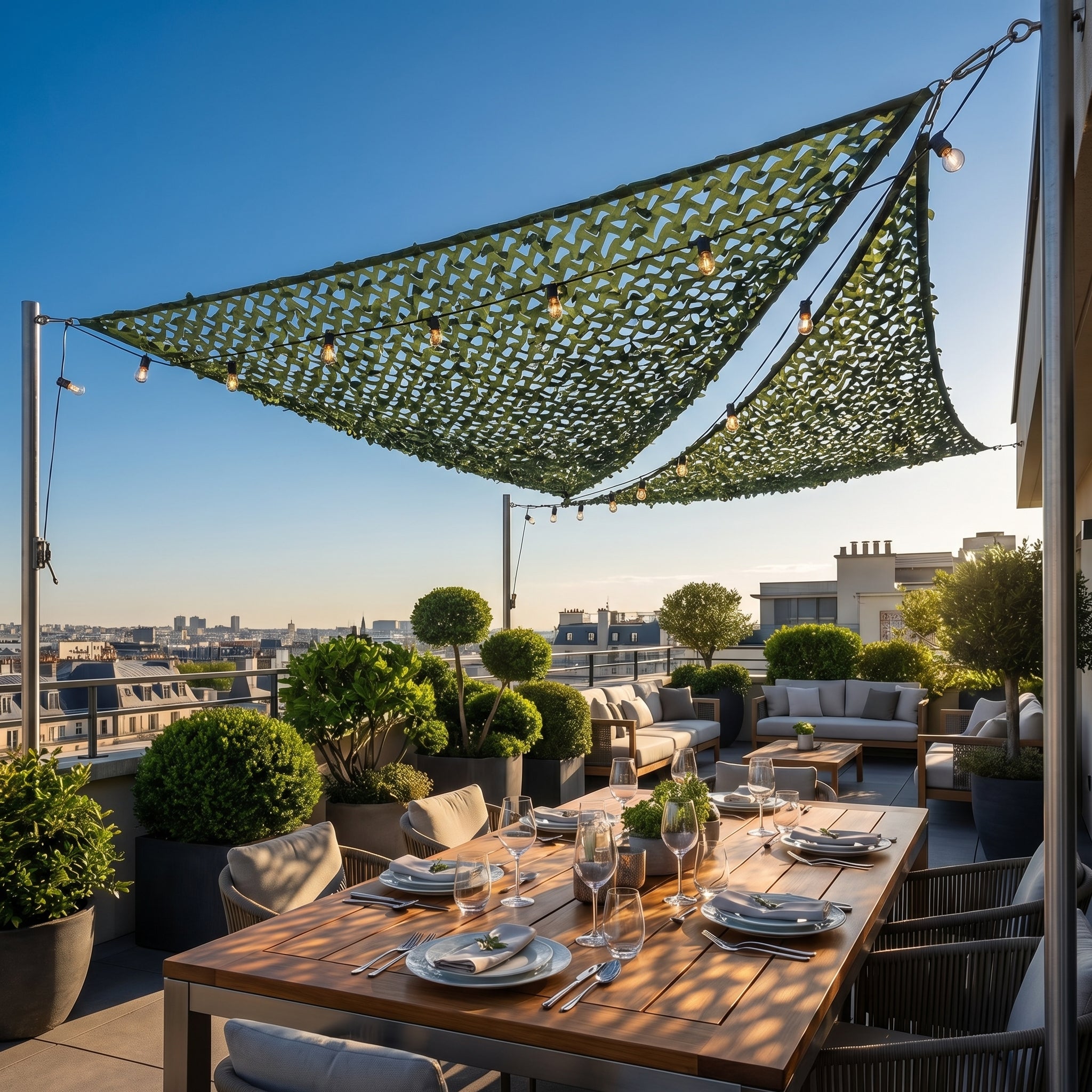Filet de camouflage triangulaire vert installé pour ombrager un salon de jardin sur une terrasse en hauteur.
