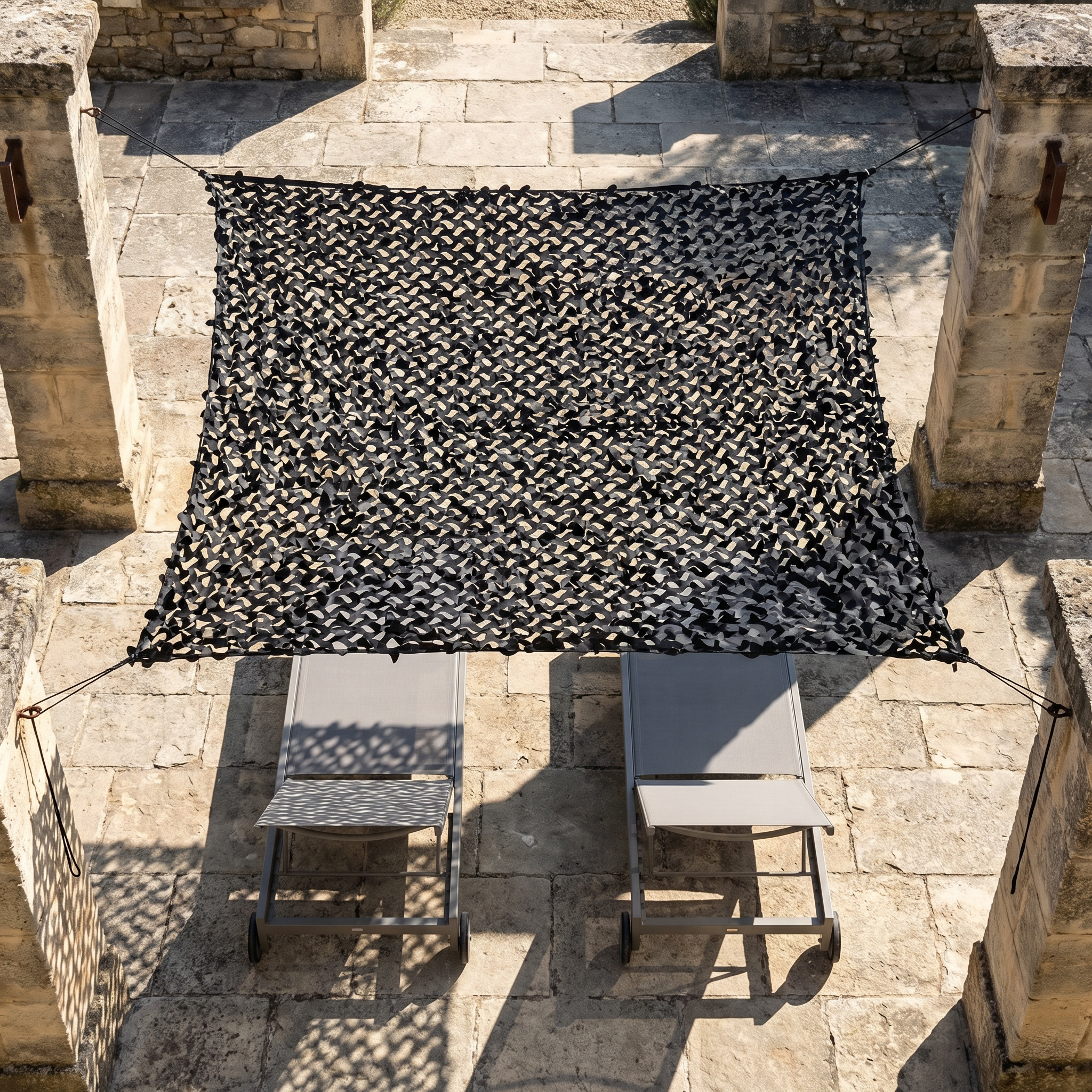 Filet de camouflage renforcé noir Camofil installé au-dessus d'une cour de terrasse moderne.