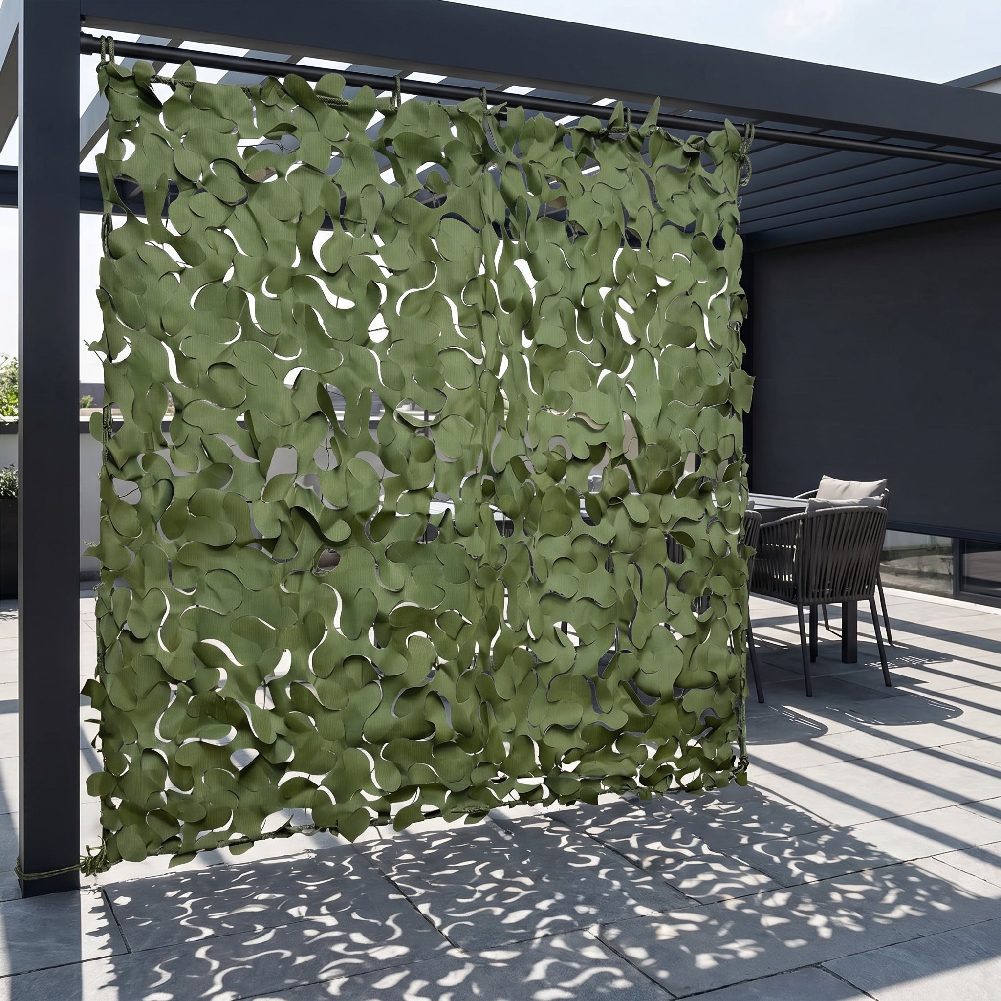 Rideau en filet de camouflage vert Camofil installé comme brise-vue vertical sur une terrasse.
