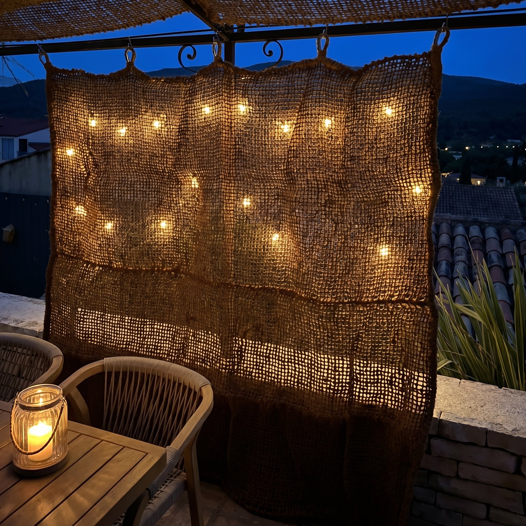 Rideau en fibre de coco éclairé par des guirlandes pour une ambiance de terrasse cosy le soir.