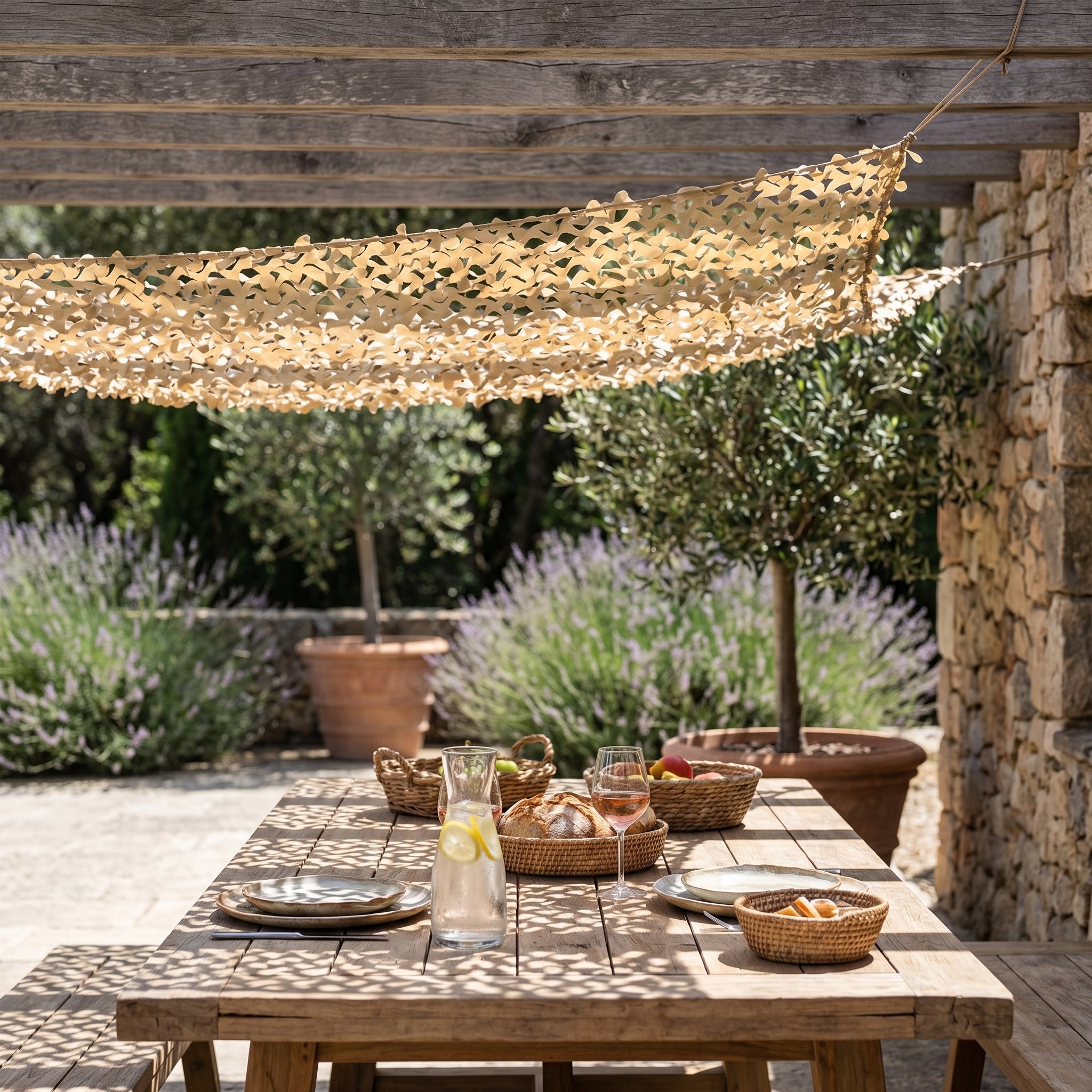Filet de camouflage renforcé sable Camofil installé sur une pergola en bois au-dessus d'une table.