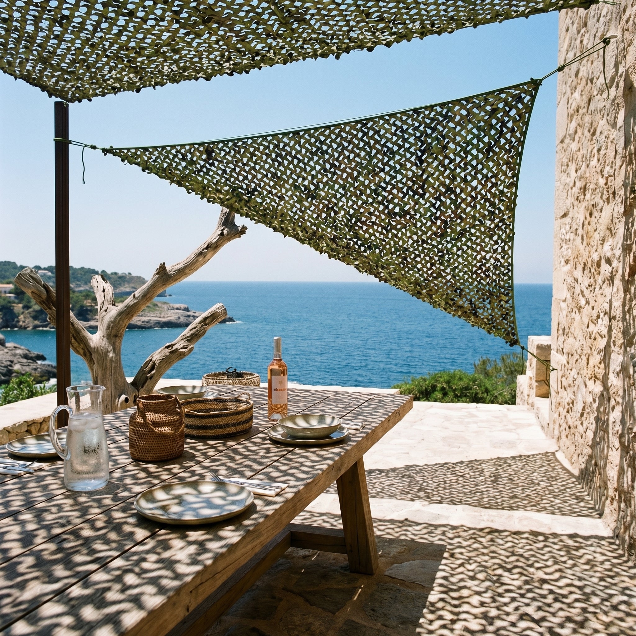 Filet de camouflage triangulaire militaire Camofil ombrageant une table de repas face à la mer.