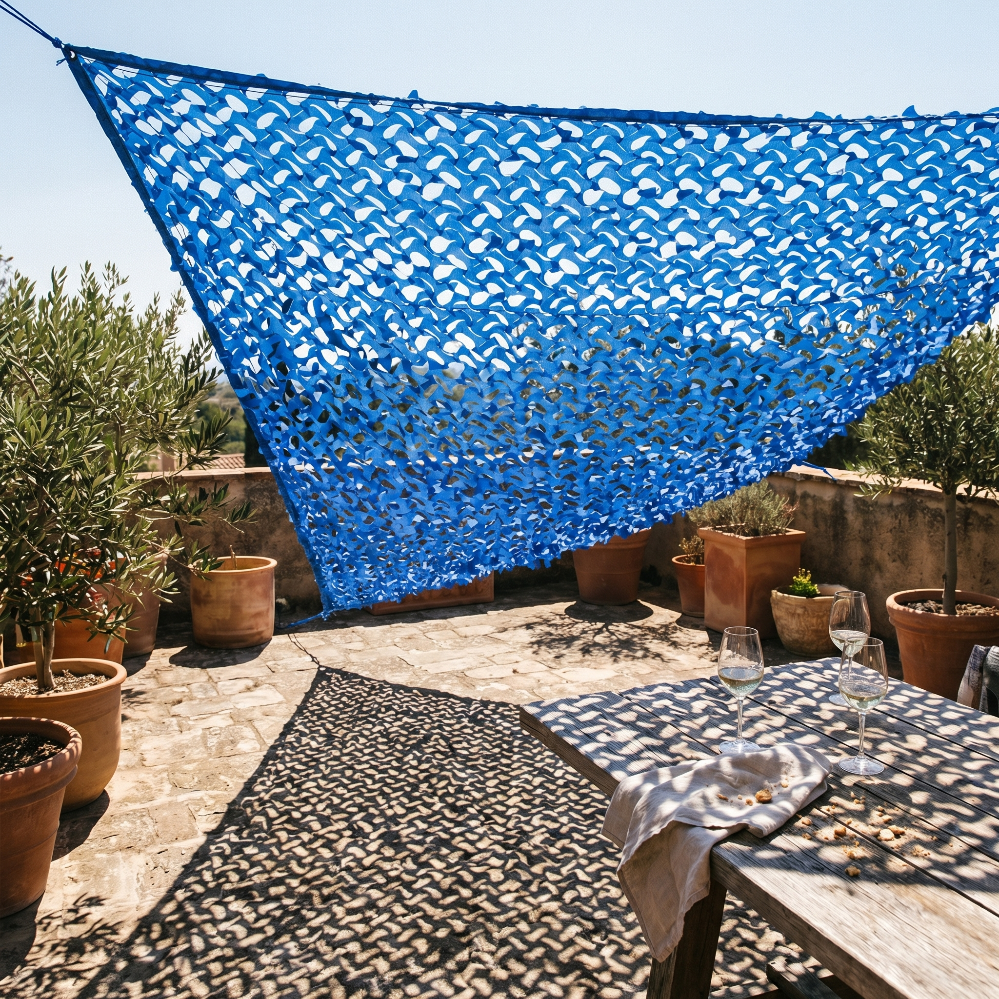 Filet de camouflage triangulaire bleu d'angle suspendu au-dessus d'un salon de jardin moderne.
