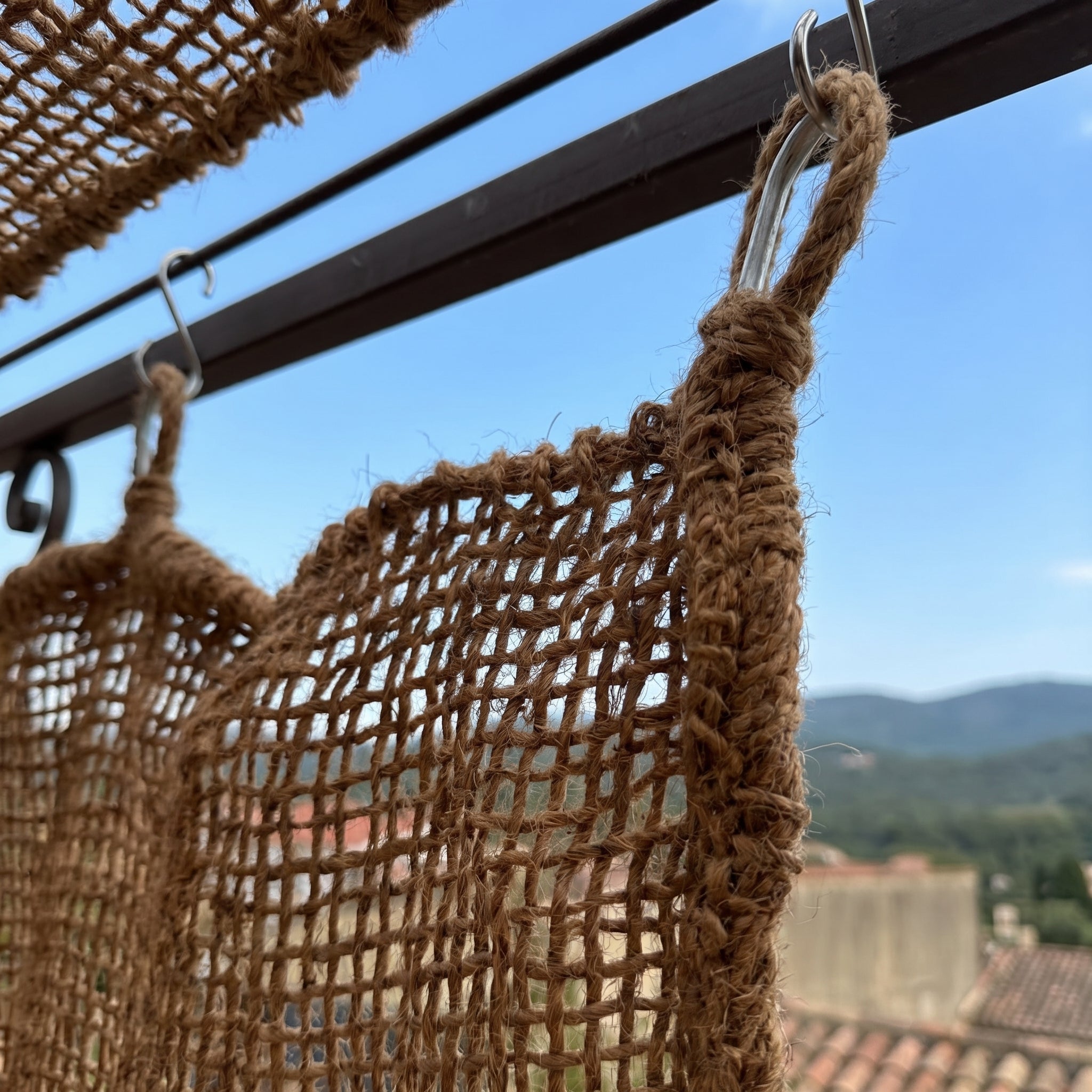 Détail de la maille naturelle d'un rideau en fibre de coco pour pergola extérieure.